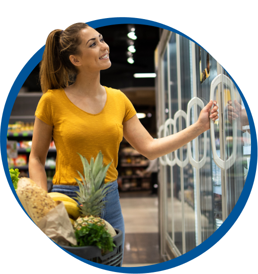 Woman browsing through glass door refrigerator in supermarket