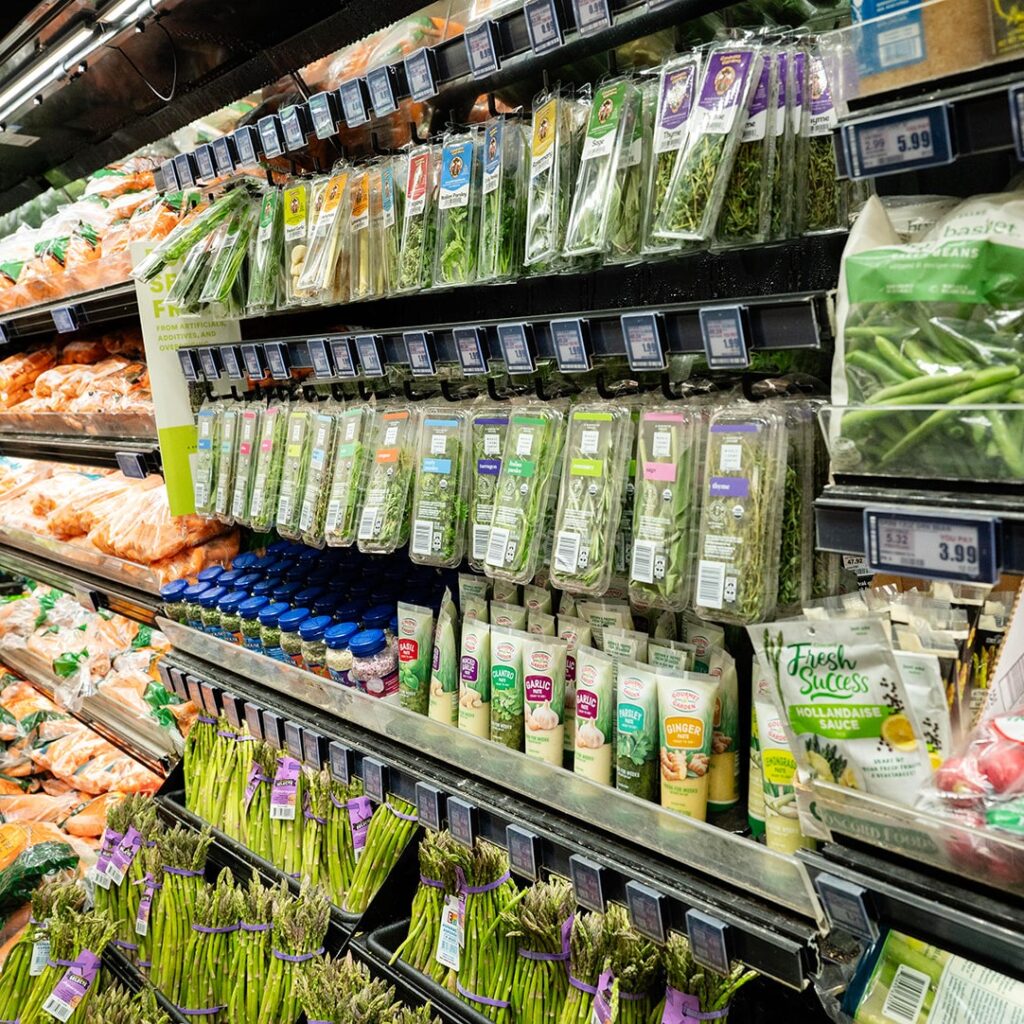 produce hanging in glass door refrigeration unit in supermarket