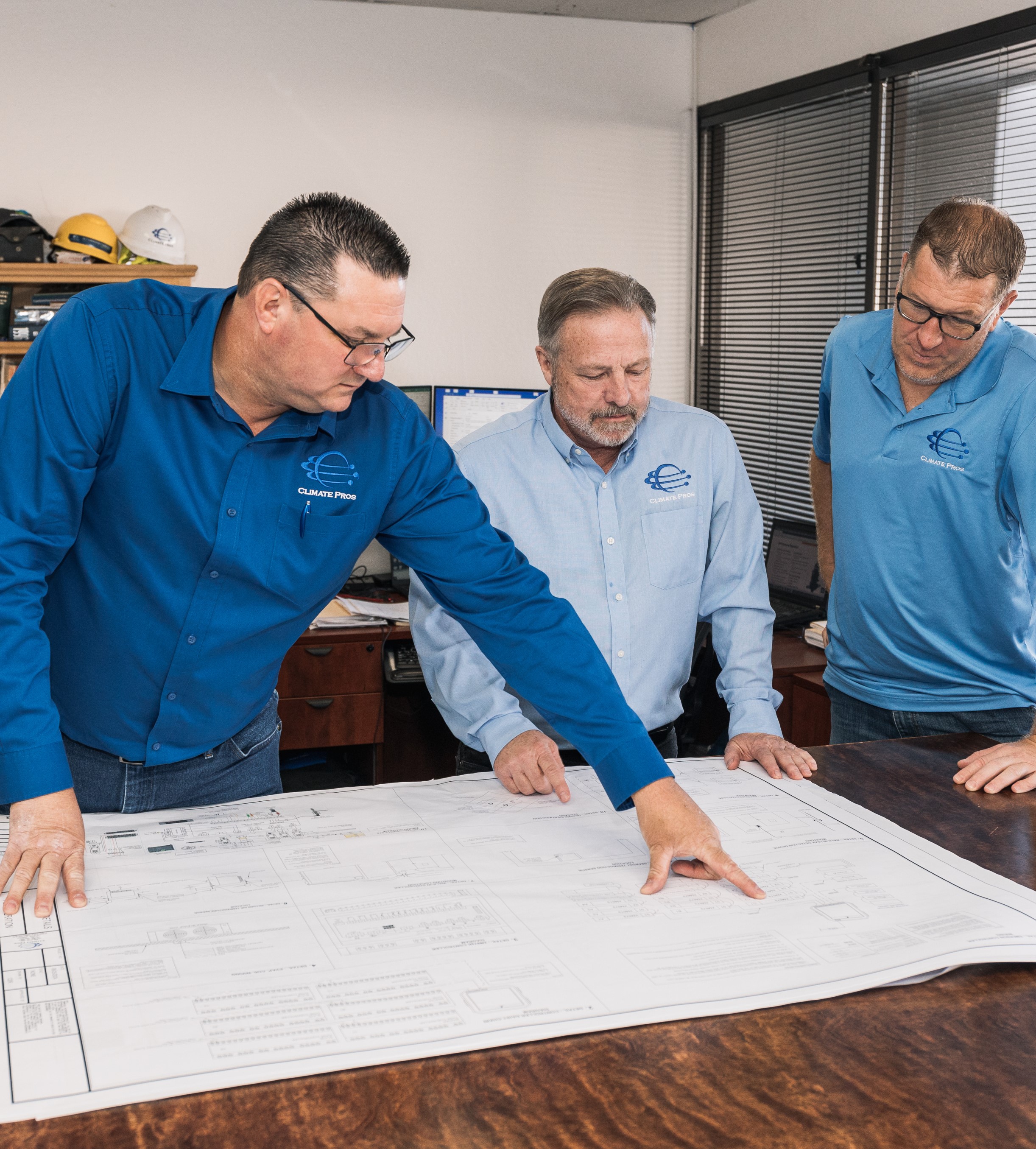 Team of engineers discussing blueprints and plans for installing refrigeration & HVAC systems