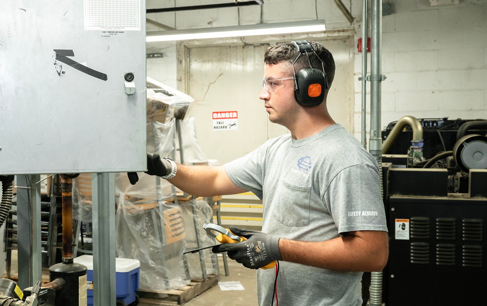 Technician wearing noise-cancelling headset while configuring systems for HVAC & refrigeration