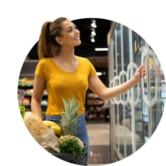 Woman browsing through glass door refrigerator in supermarket